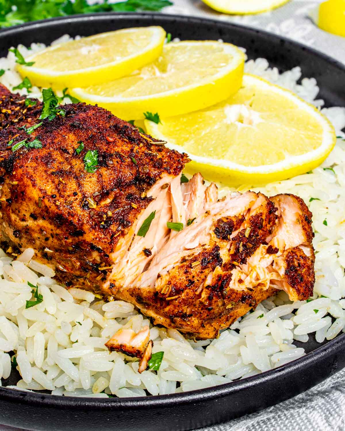 a salmon fillet on a bed of rice with lemon slices.