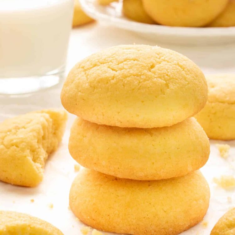 a stack of amish sugar cookies next to a glass of milk.