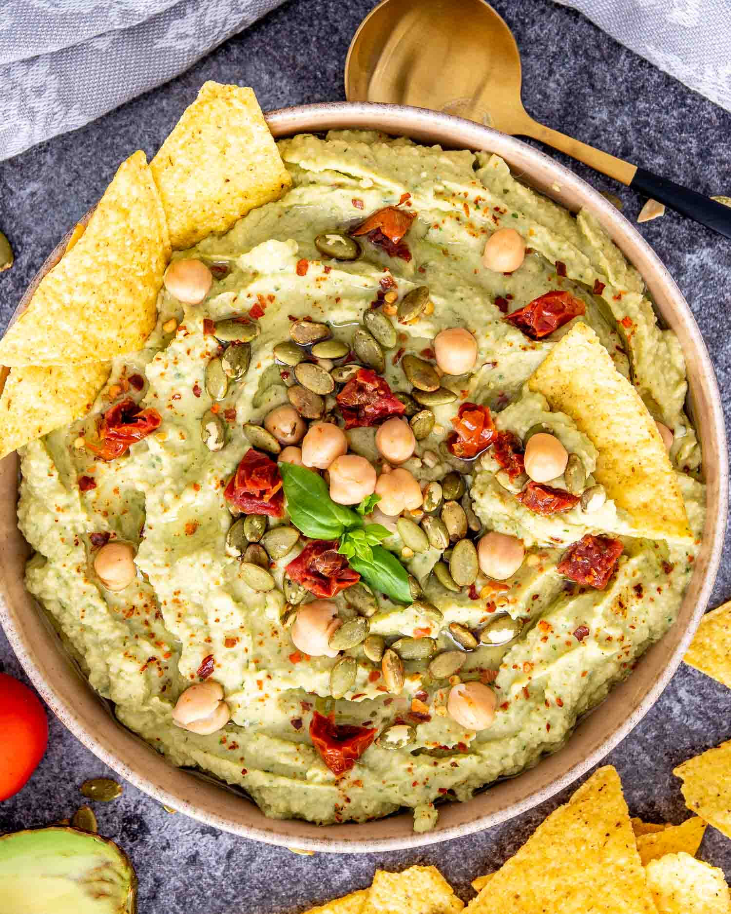 avocado basil dip in a bowl with tortilla chips.