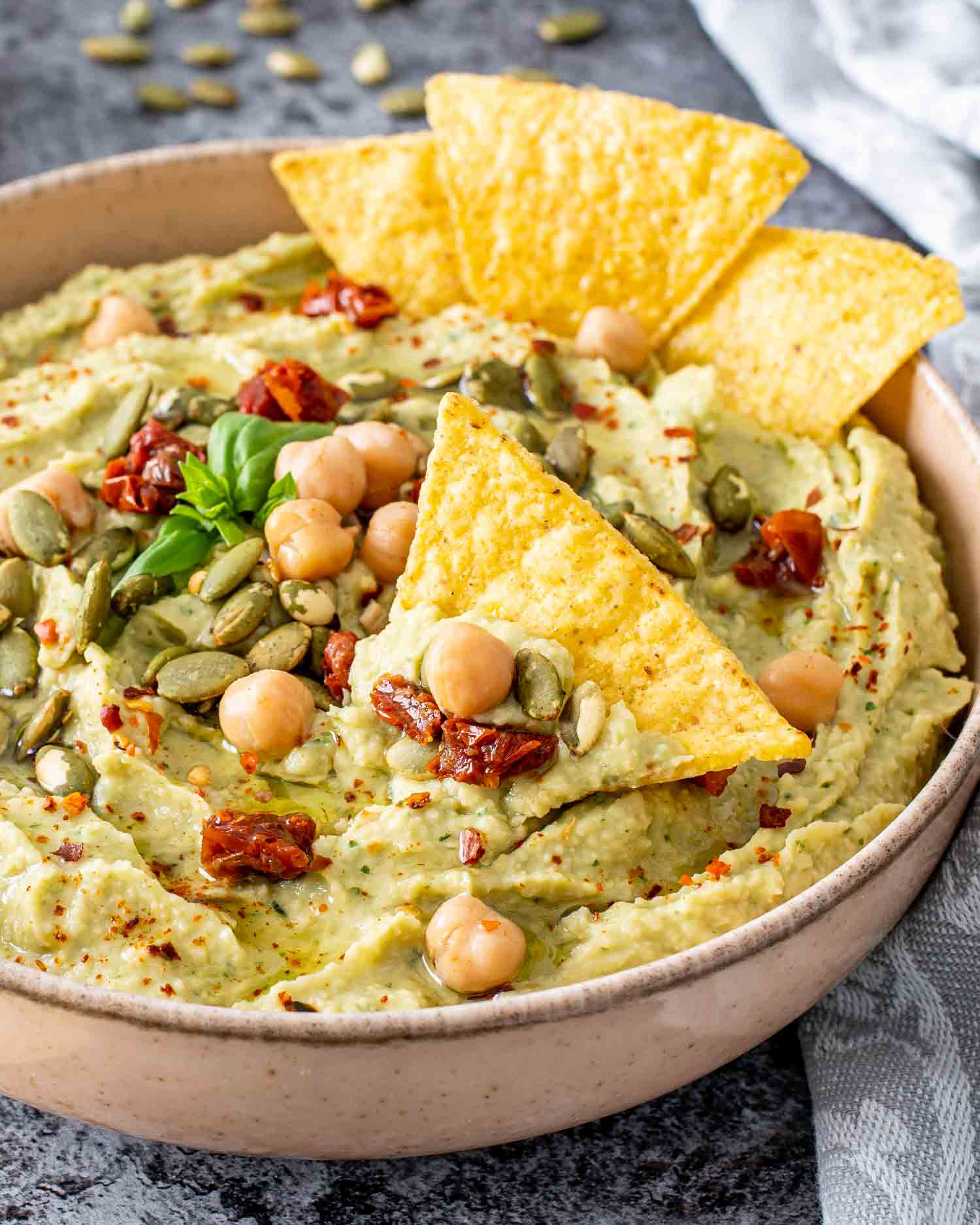 avocado basil dip in a bowl with tortilla chips.