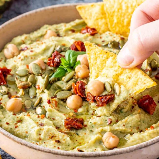 avocado basil dip in a bowl with tortilla chips.