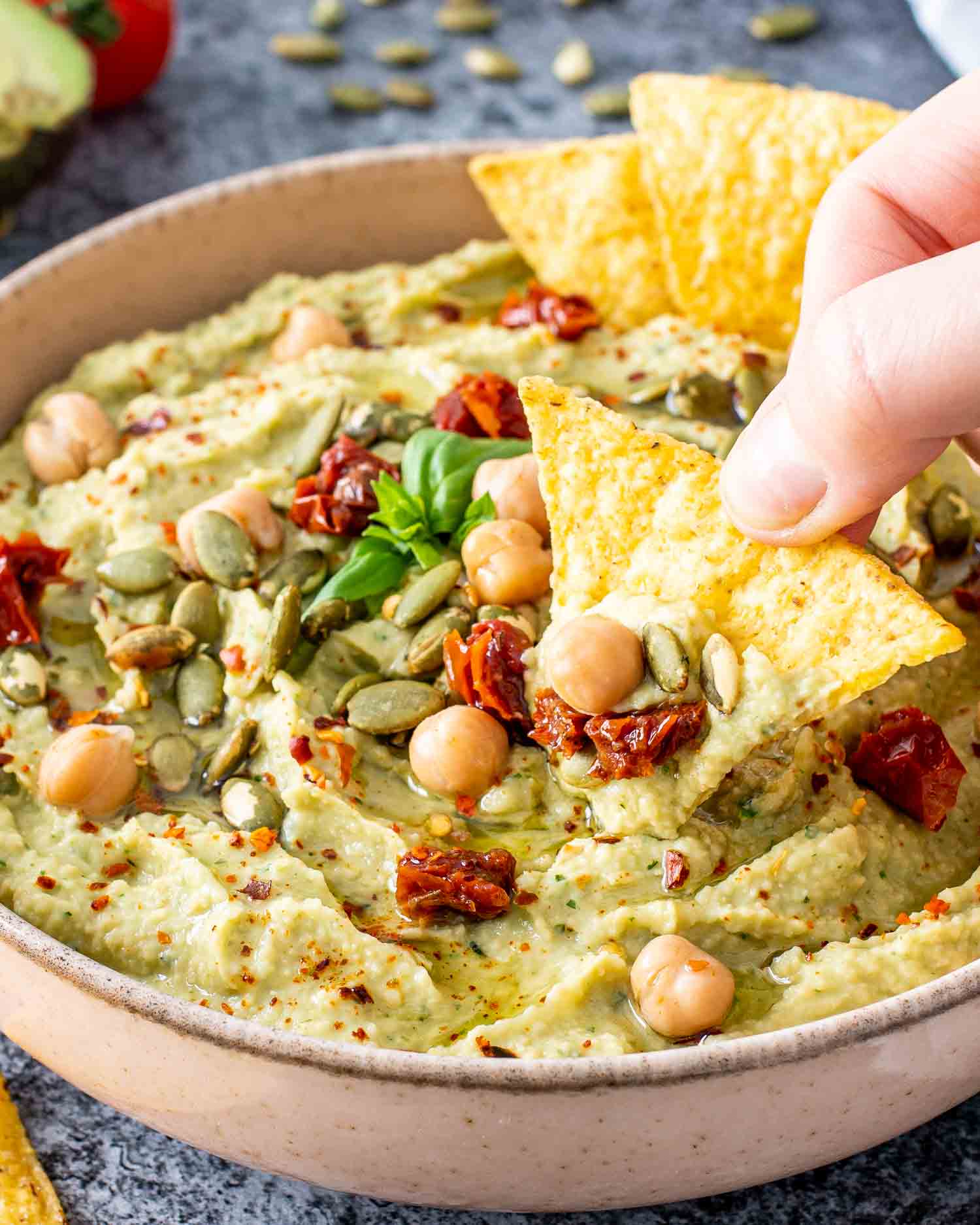 avocado basil dip in a bowl with tortilla chips.