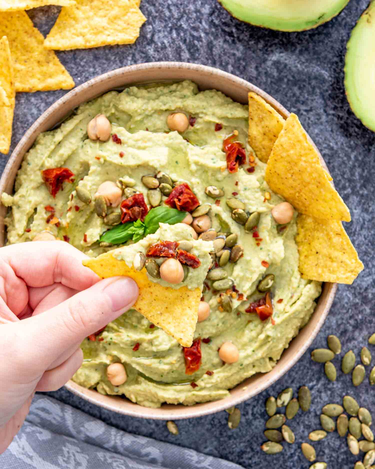 avocado basil dip in a bowl with tortilla chips.