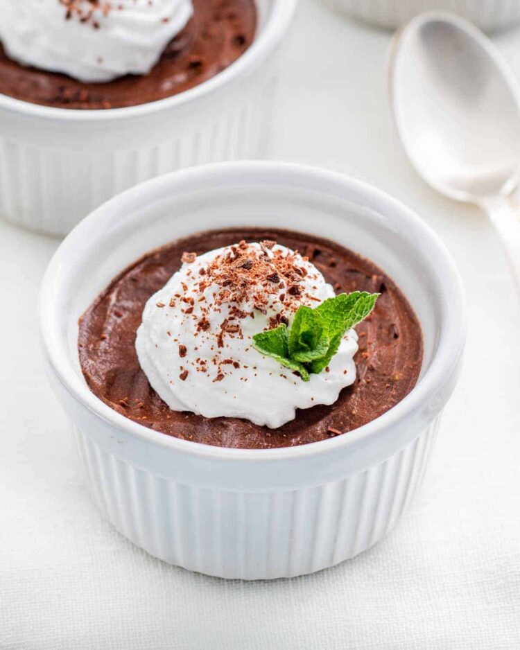 avocado chocolate mousse in a white ramekin topped with whipped cream