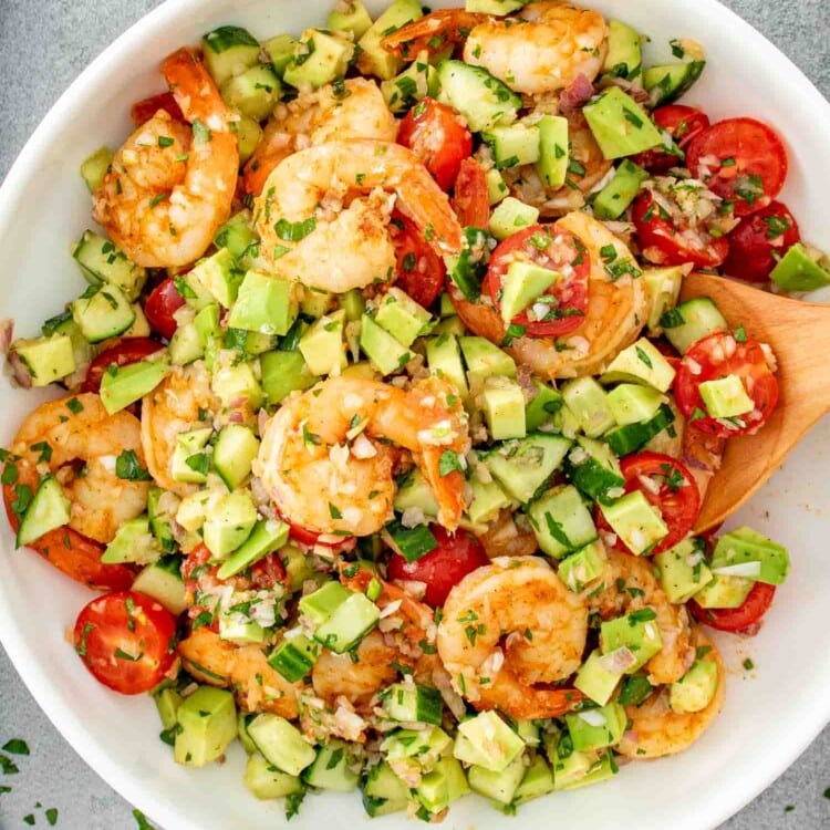 a big fresh shrimp avocado salad in a white bowl.