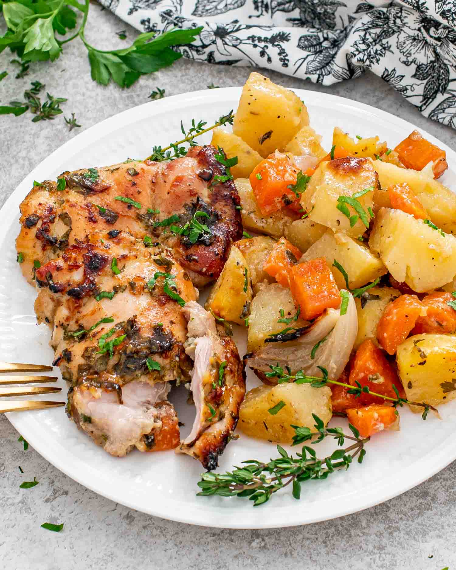 a serving of baked honey mustard chicken with potatoes on a white plate.