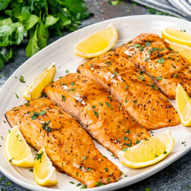 baked salmon fillets with mustard glaze on a white platter.