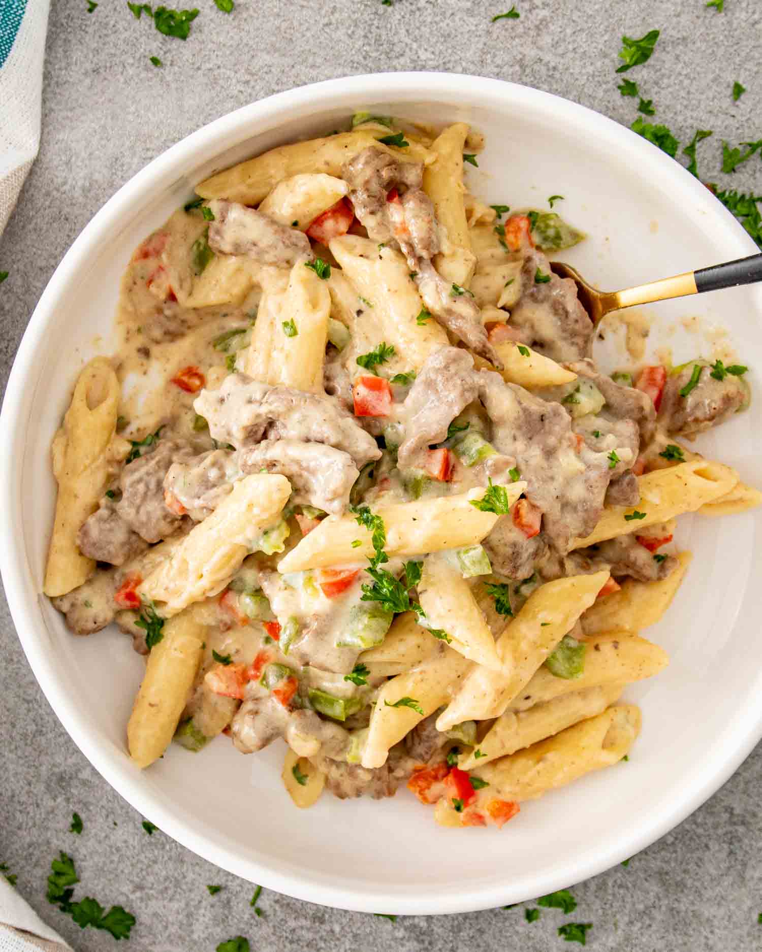 a serving of creamy dreamy cheesesteak pasta in a white bowl.