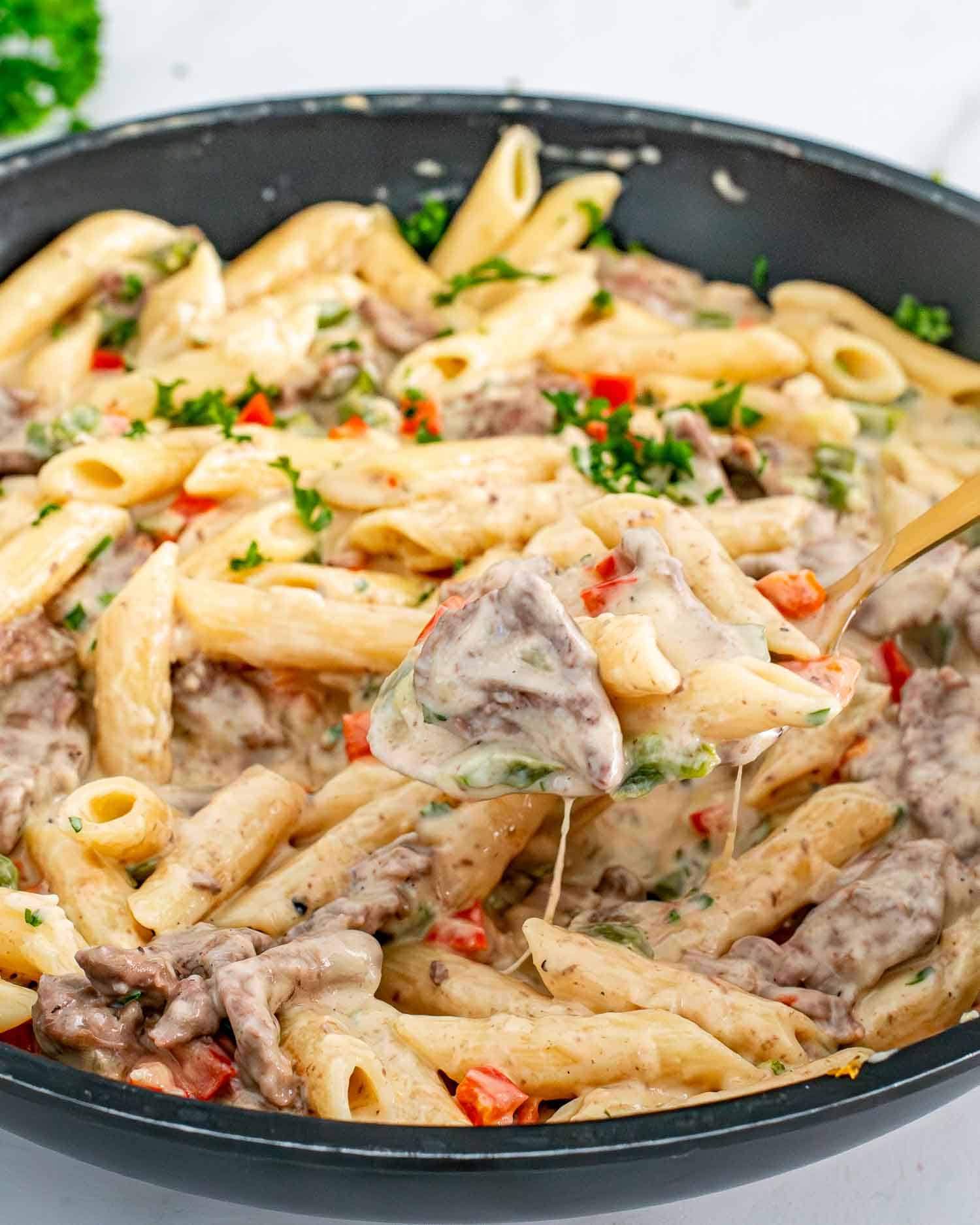 creamy cheesy cheesesteak pasta in a skillet.