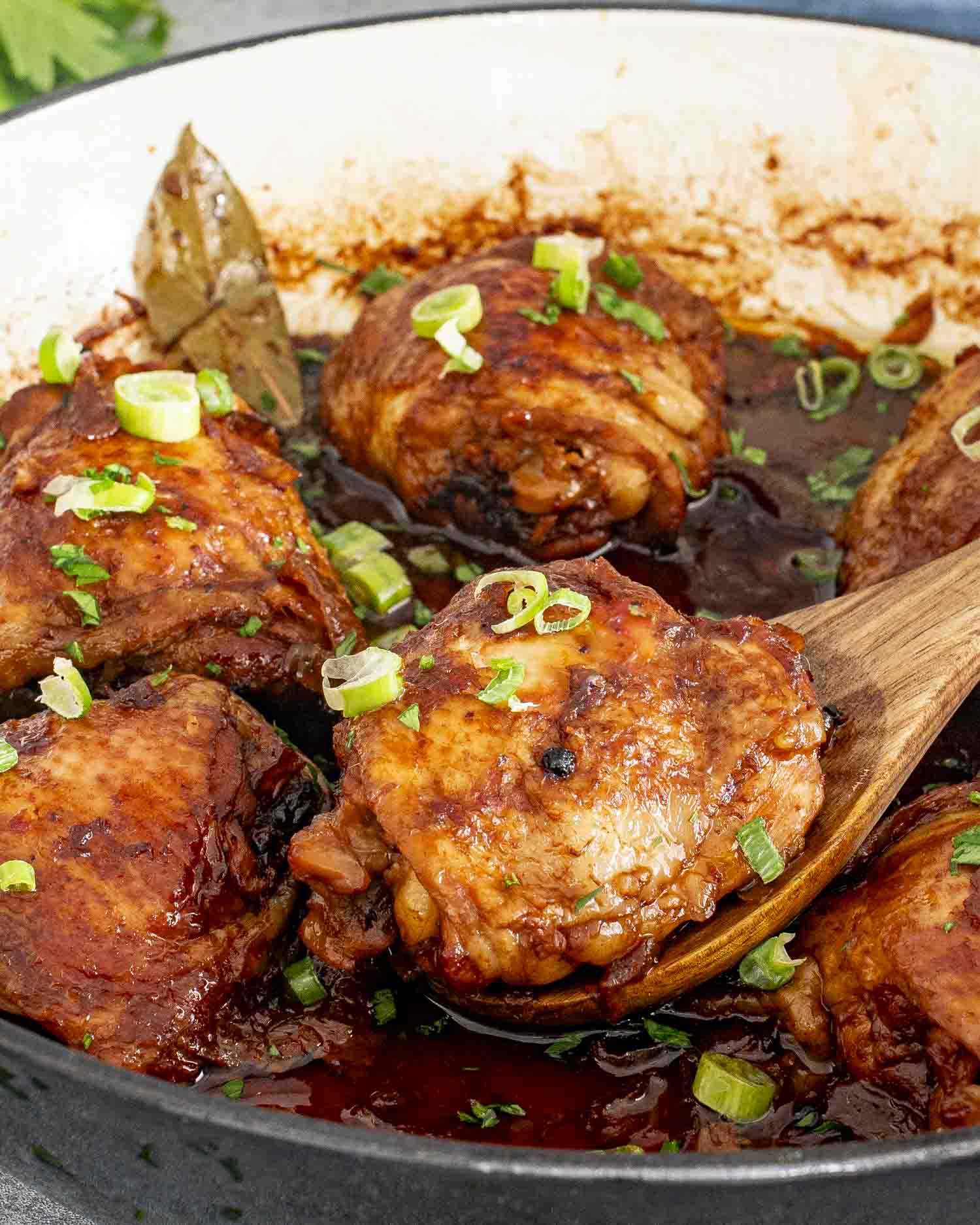chicken adobo in a skillet garnished with green onions.