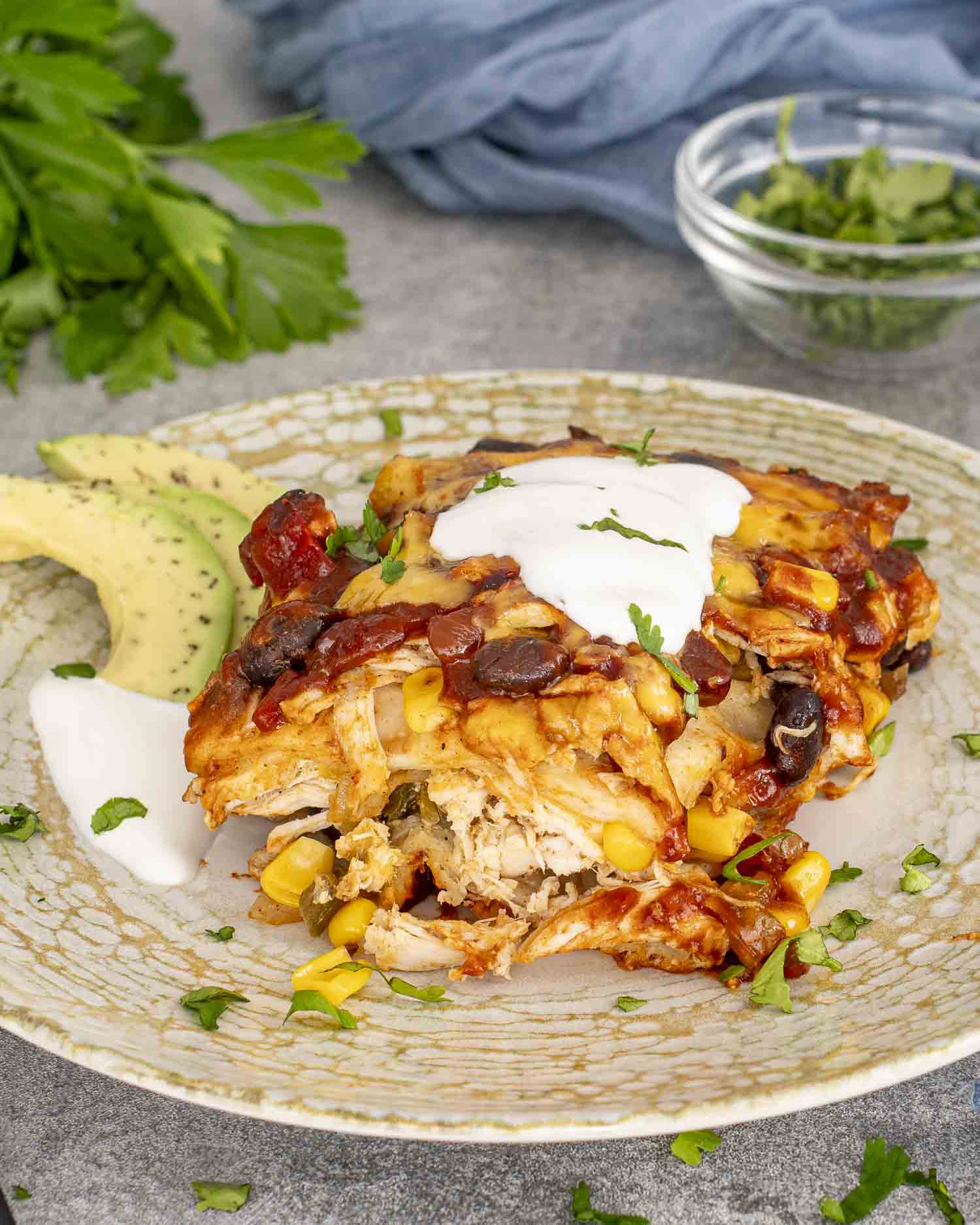 a slice of chicken enchilada casserole on a plate with a dollop of sour cream.