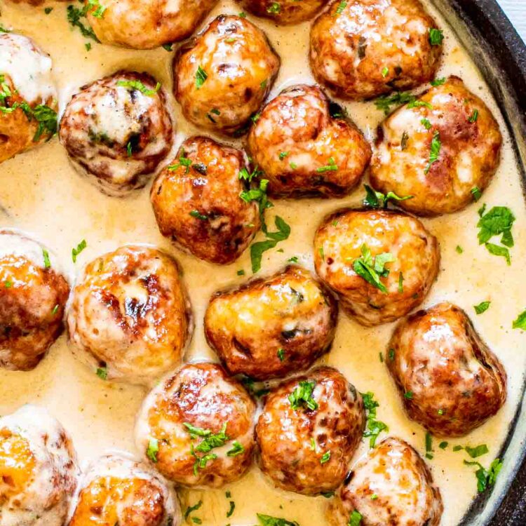 chicken meatballs in alfredo sauce in a skillet.