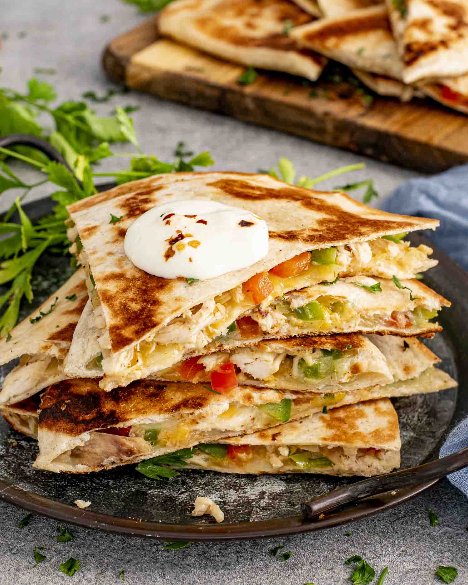 a stack of chicken quesadillas on a board with a bowl of salsa in the background.