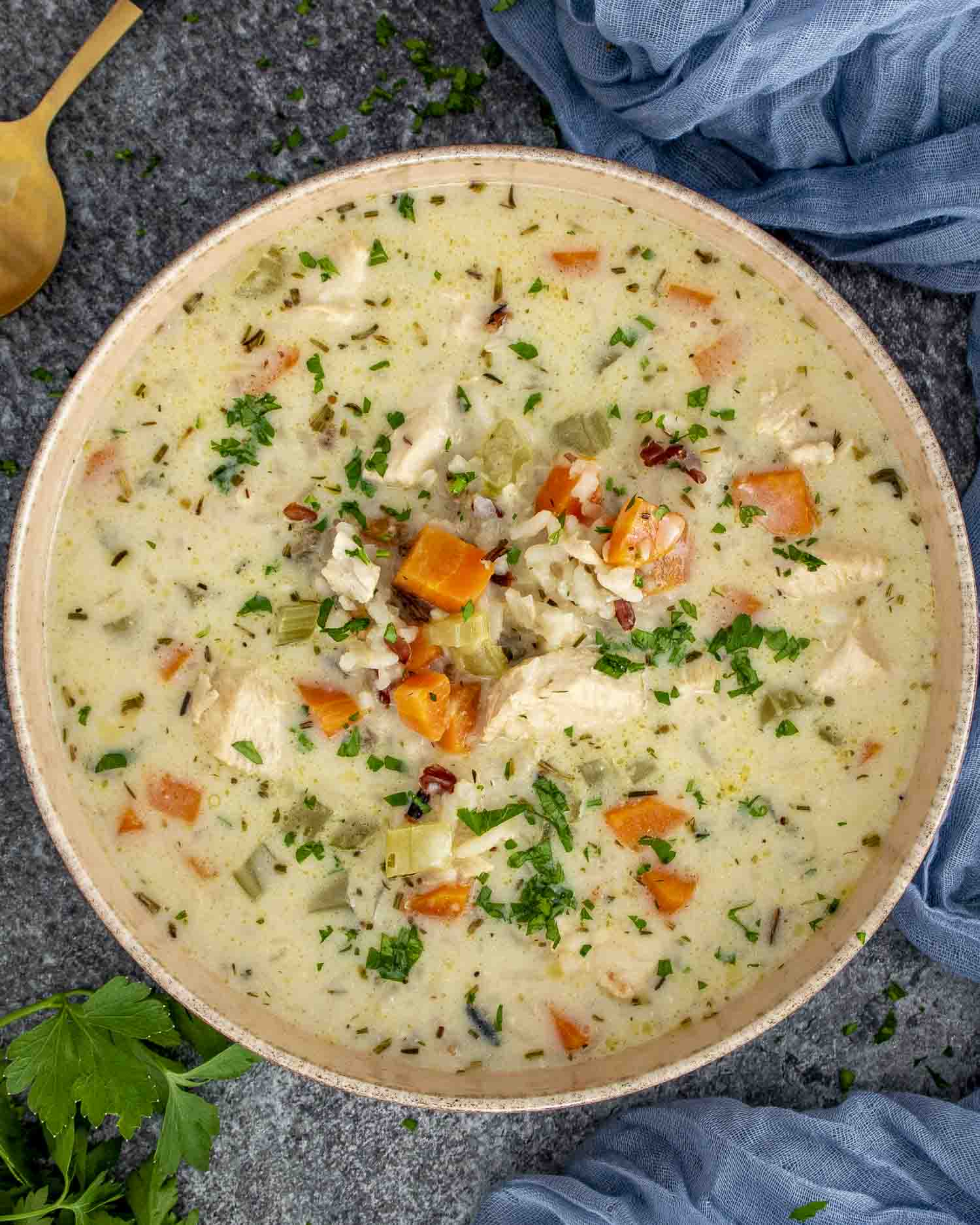 A warm, comforting bowl of creamy chicken wild rice soup, filled with tender chunks of chicken, diced carrots, celery, and wild rice in a rich, herb-infused broth.