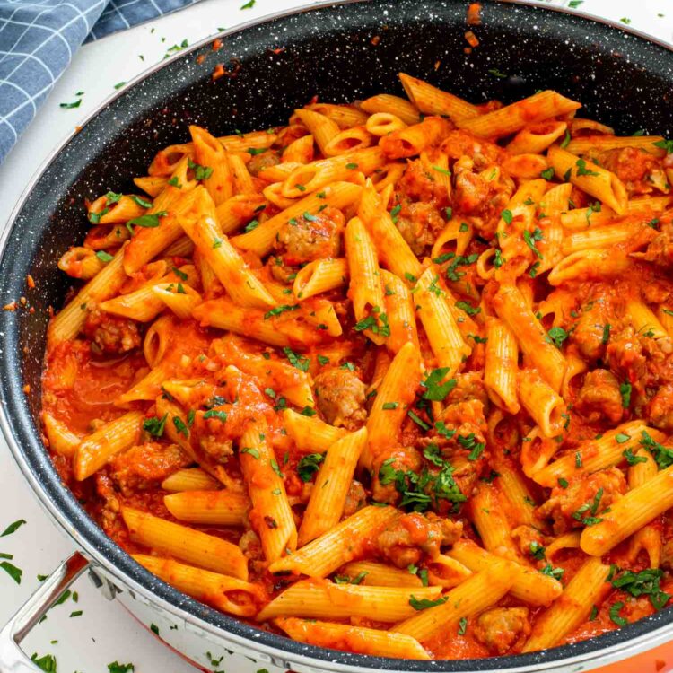 freshly made creamy red pepper pasta in an orange skillet.
