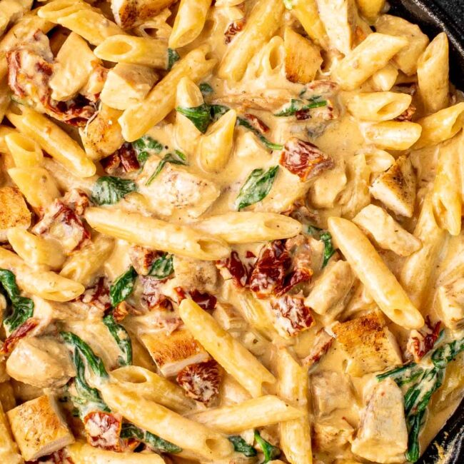 creamy tuscan chicken pasta in a black skillet.