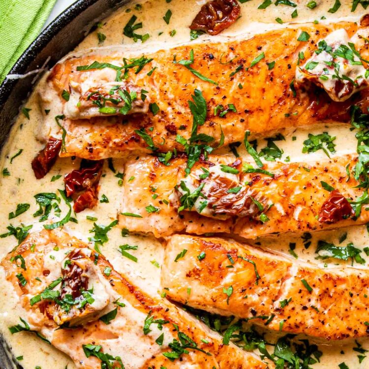 closeup of creamy tuscan salmon in a black skillet.