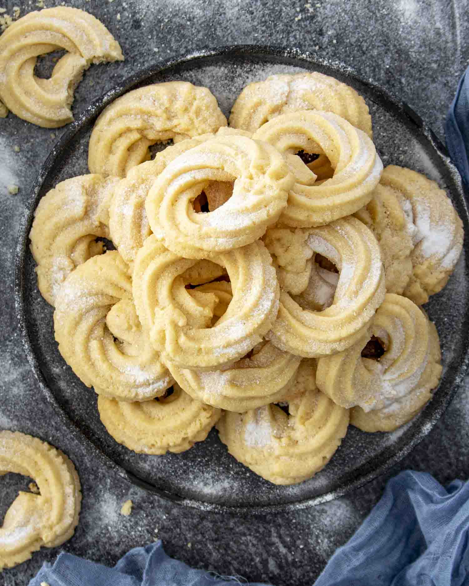 freshly made danish butter cookies dusted with powdered sugar on a plate.