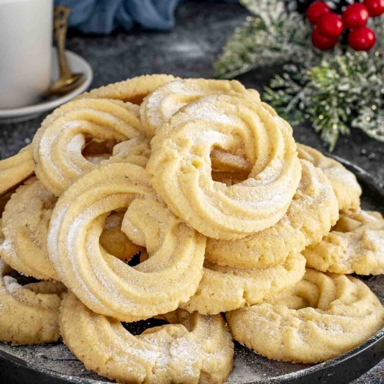 freshly made danish butter cookies dusted with powdered sugar on a plate.