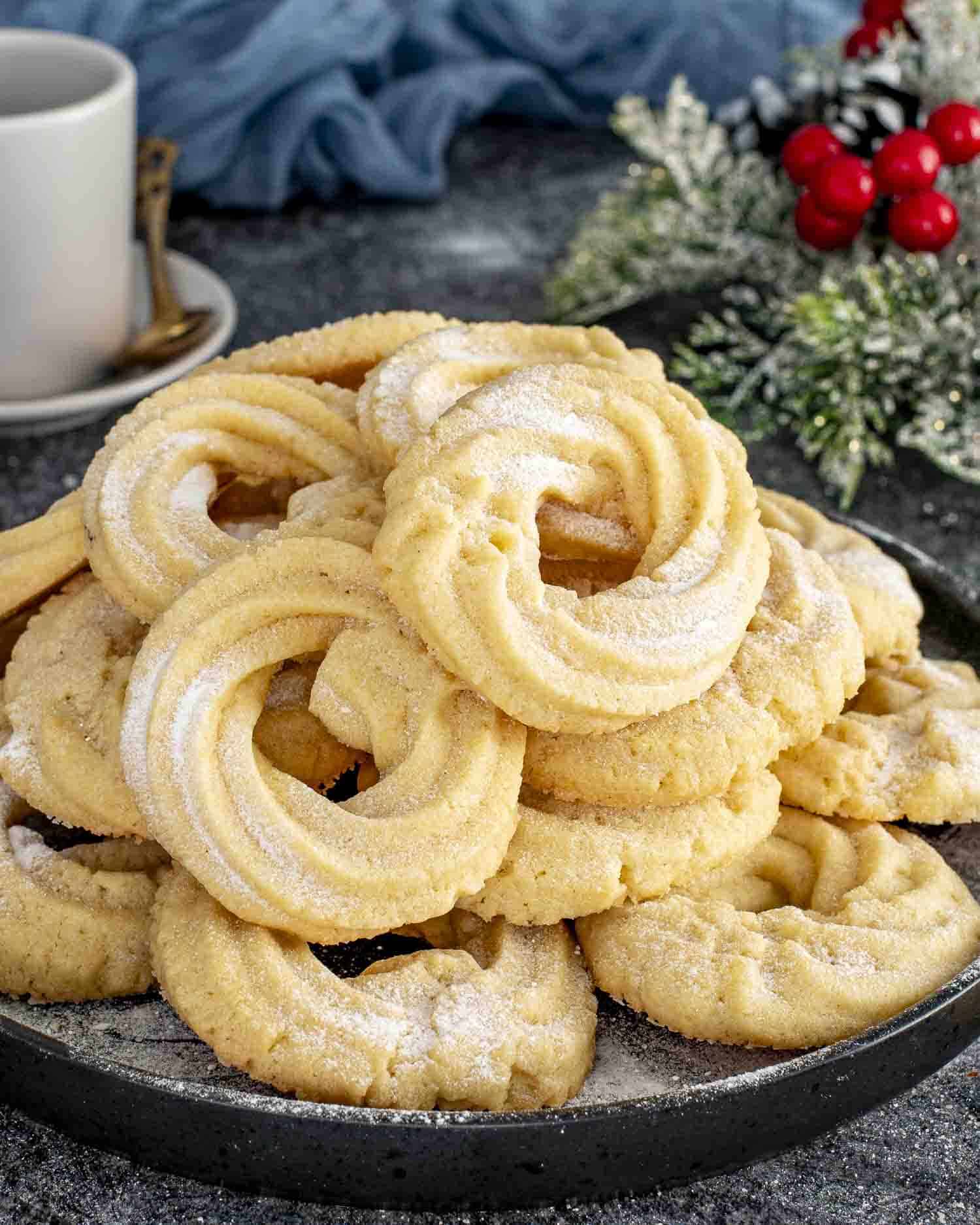 freshly made danish butter cookies dusted with powdered sugar on a plate.