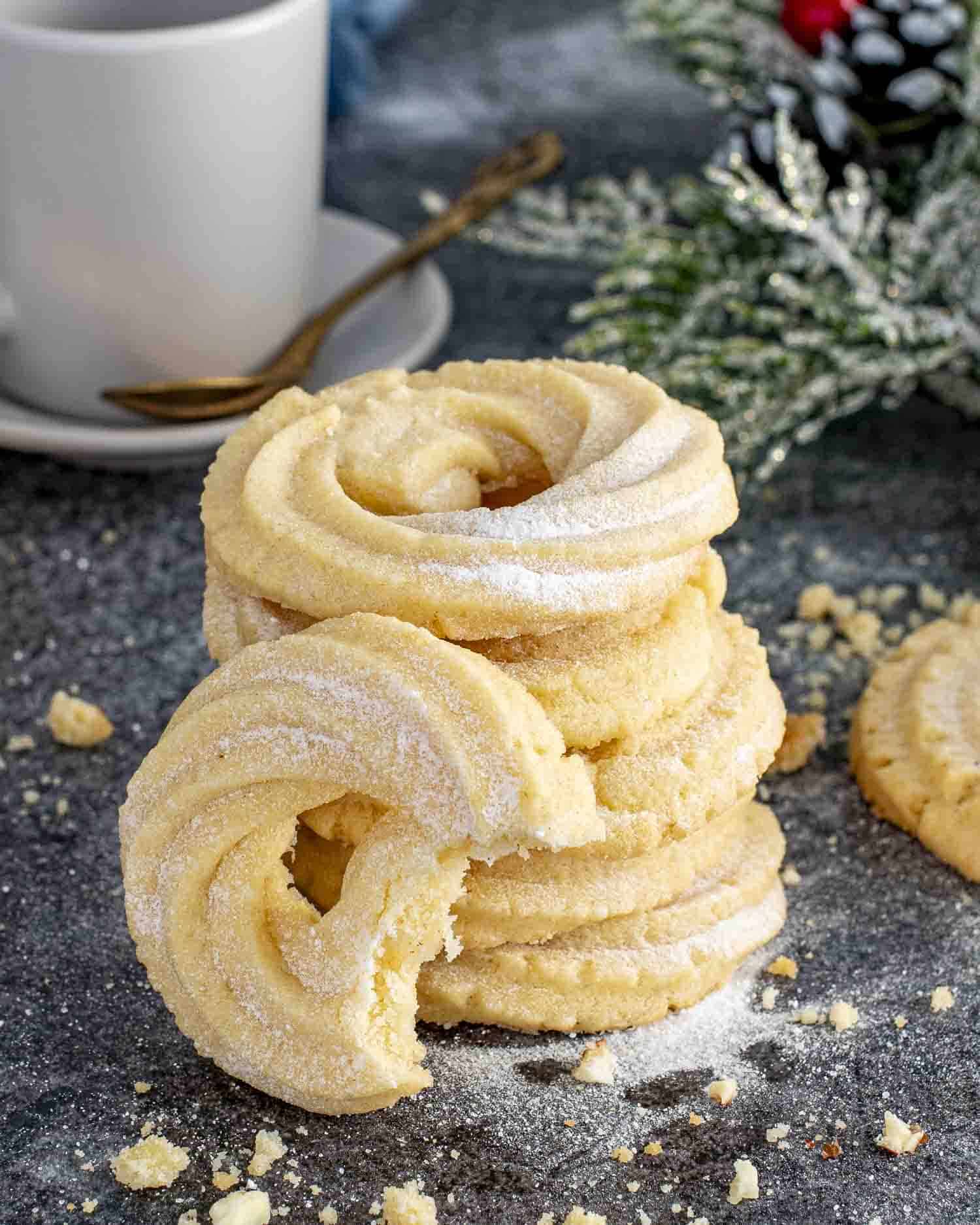 a stack of danish butter cookies with a cup of coffee in the background.