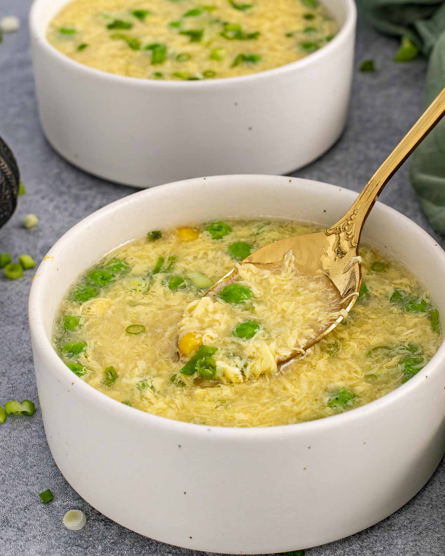 a bowl of freshly made egg drop soup with a spoon inside.