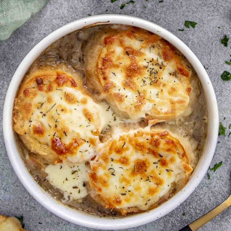 two bowls with french onion soup each bowl with 3 slices of toasted bread with cheese.
