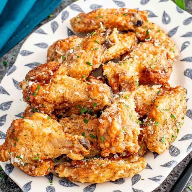freshly made garlic parmesan wings on a white plate.