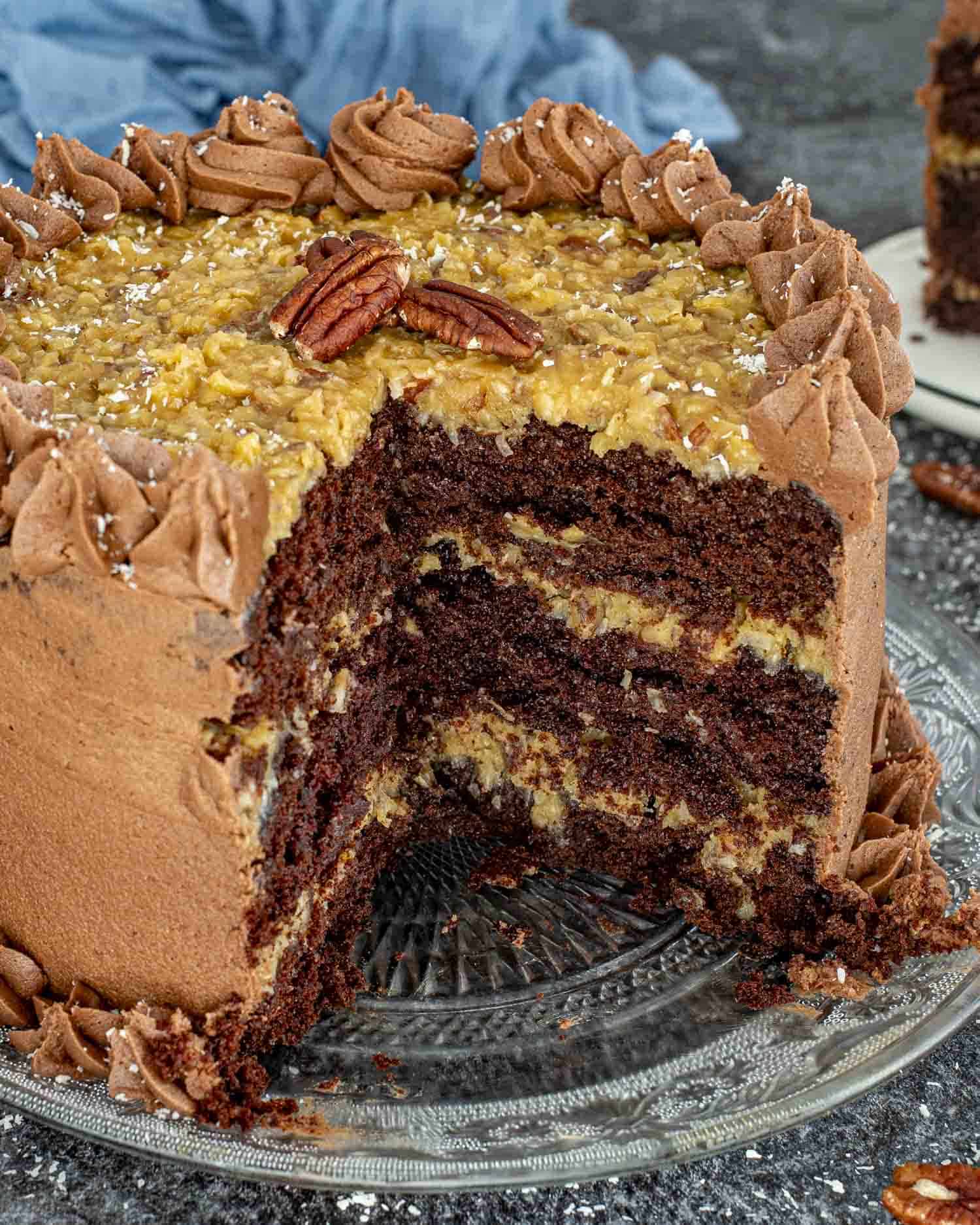 a german chocolate cake on a cake platter with a couple slices cut out of it.