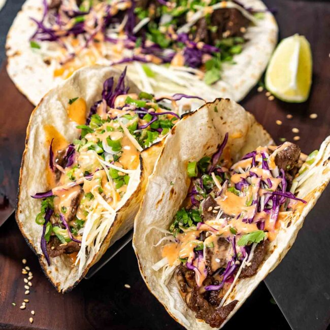 two korean beef tacos on a taco stand.
