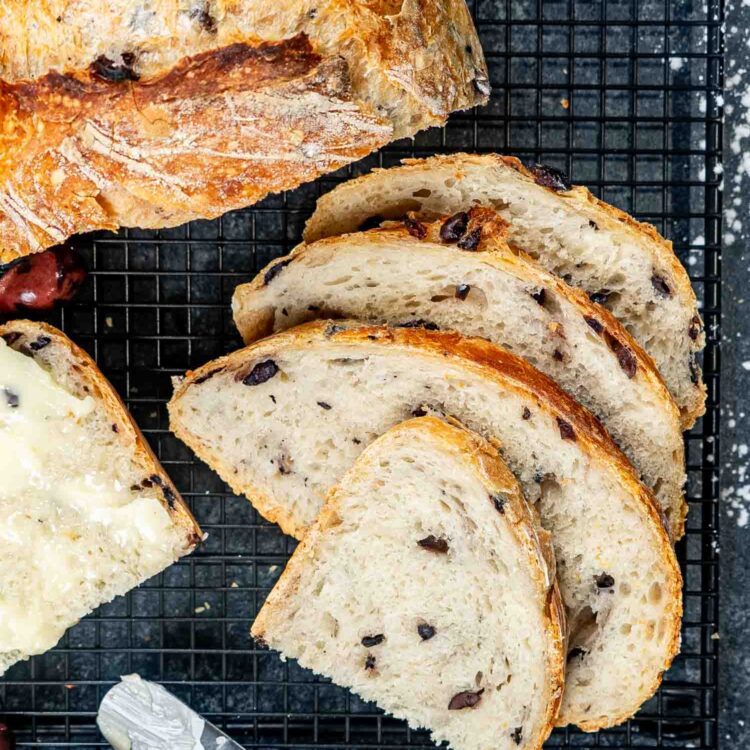 slices of no knead olive bread next to the half loaf.