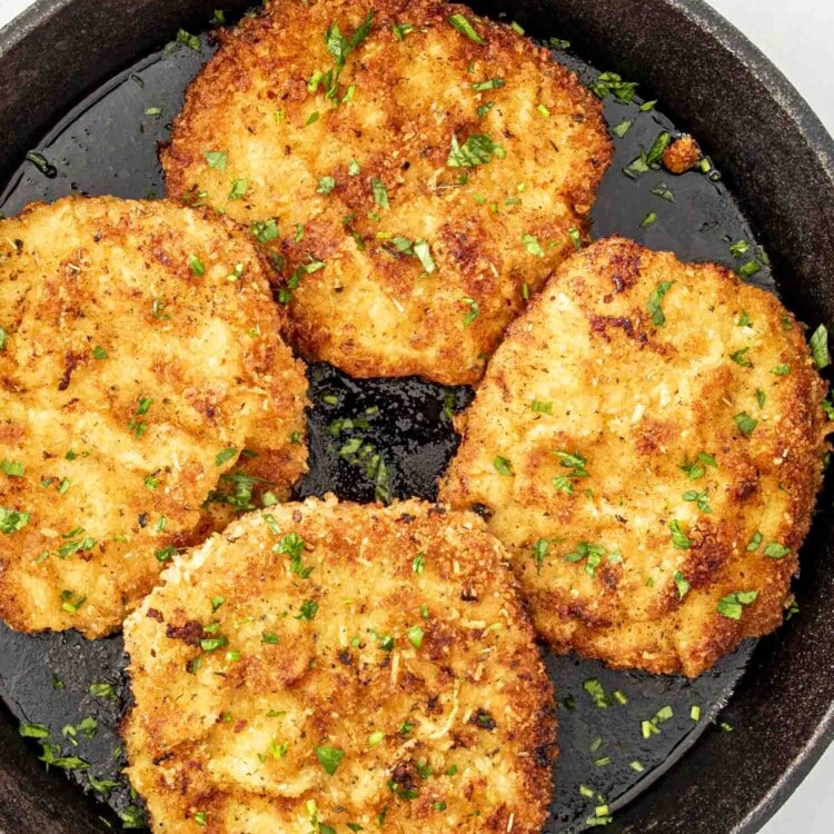 freshly made parmesan crusted pork chops in a skillet.