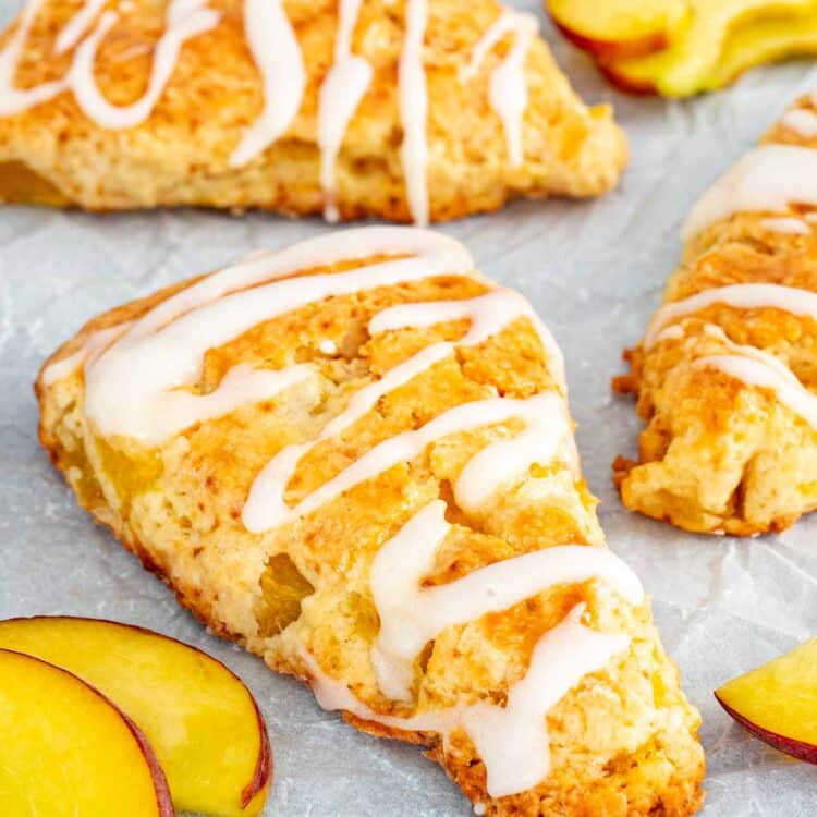 peach scones drizzled with icing on parchment paper.