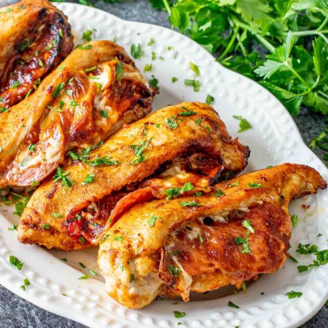pizza stuffed chicken breasts on a white serving platter.