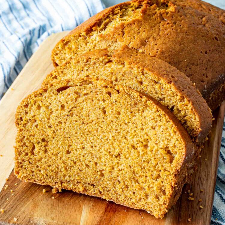 pumpkin bread with a couple slices cut out of it on a cutting board.