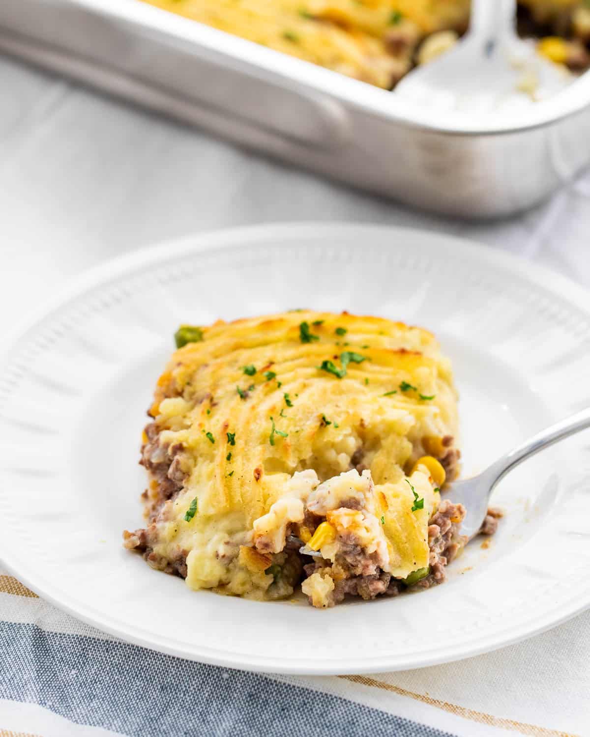 a white plate with a slice of shepherd's pie with a fork in it