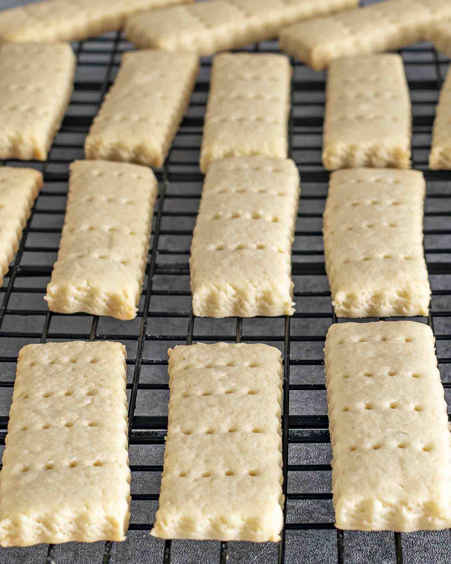 freshly baked shortbread cookies cooling on a black cooling rack.
