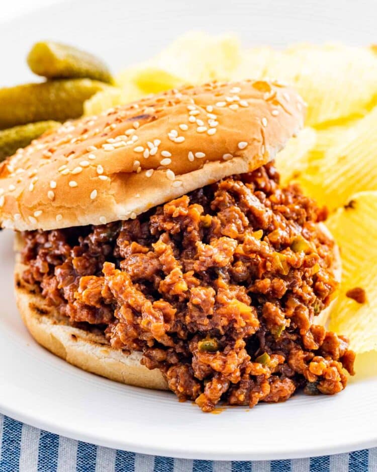 a sloppy joe sandwich with chips on a plate