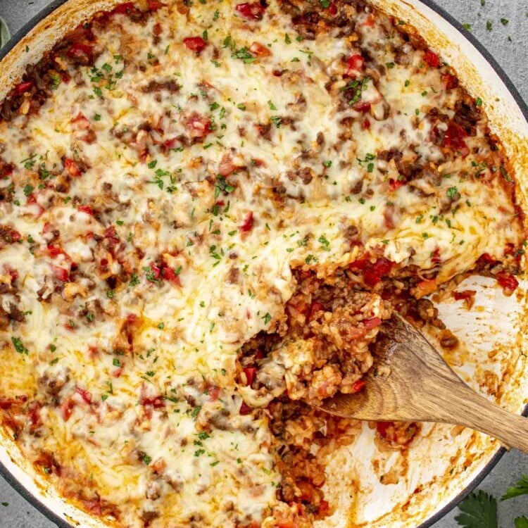 fresh out of the oven, stuffed pepper casserole in a pot topped with cheese and a sprinkle of parsley.