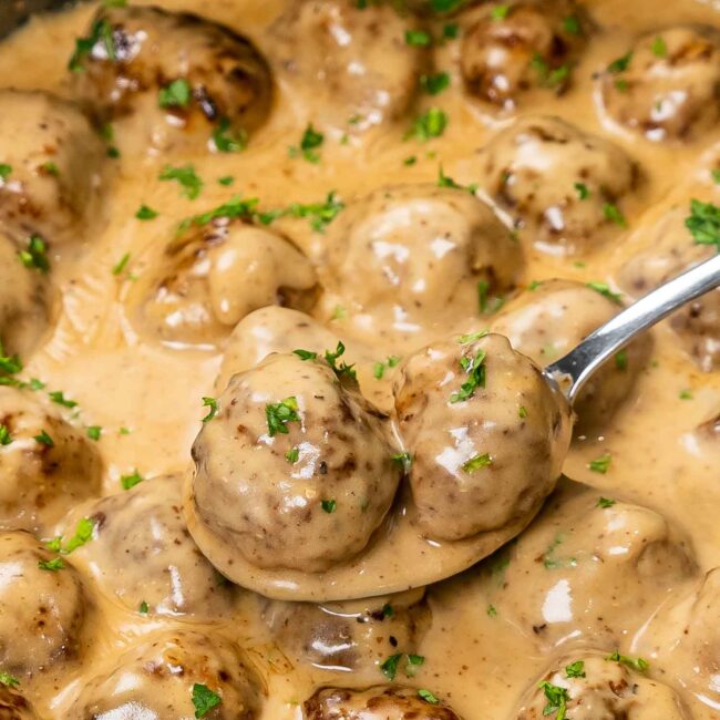 swedish meatballs with lots of sauce in a skillet, freshly made and garnished with parsley.