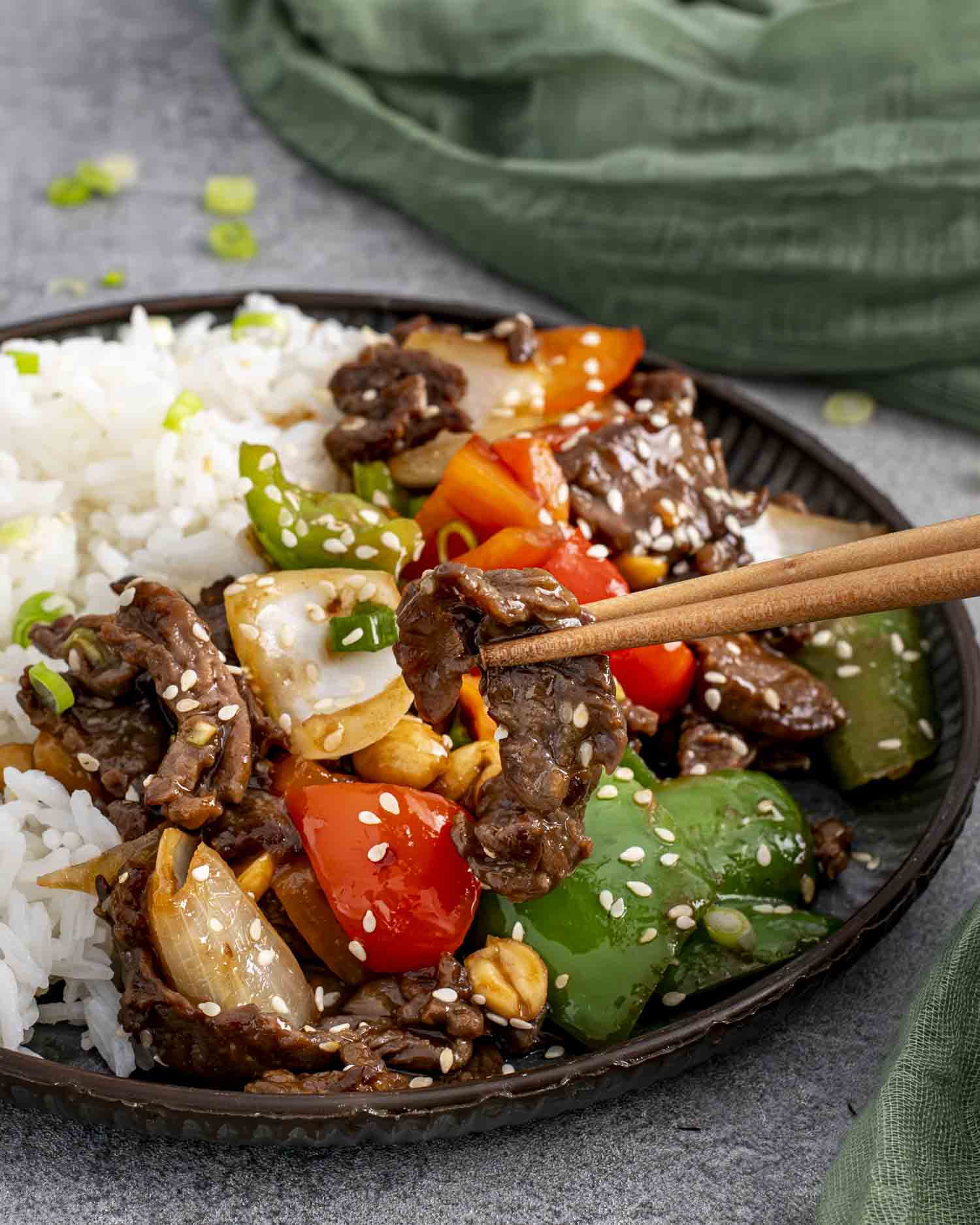 szechuan beef with rice on a plate garnished with sesame seeds.