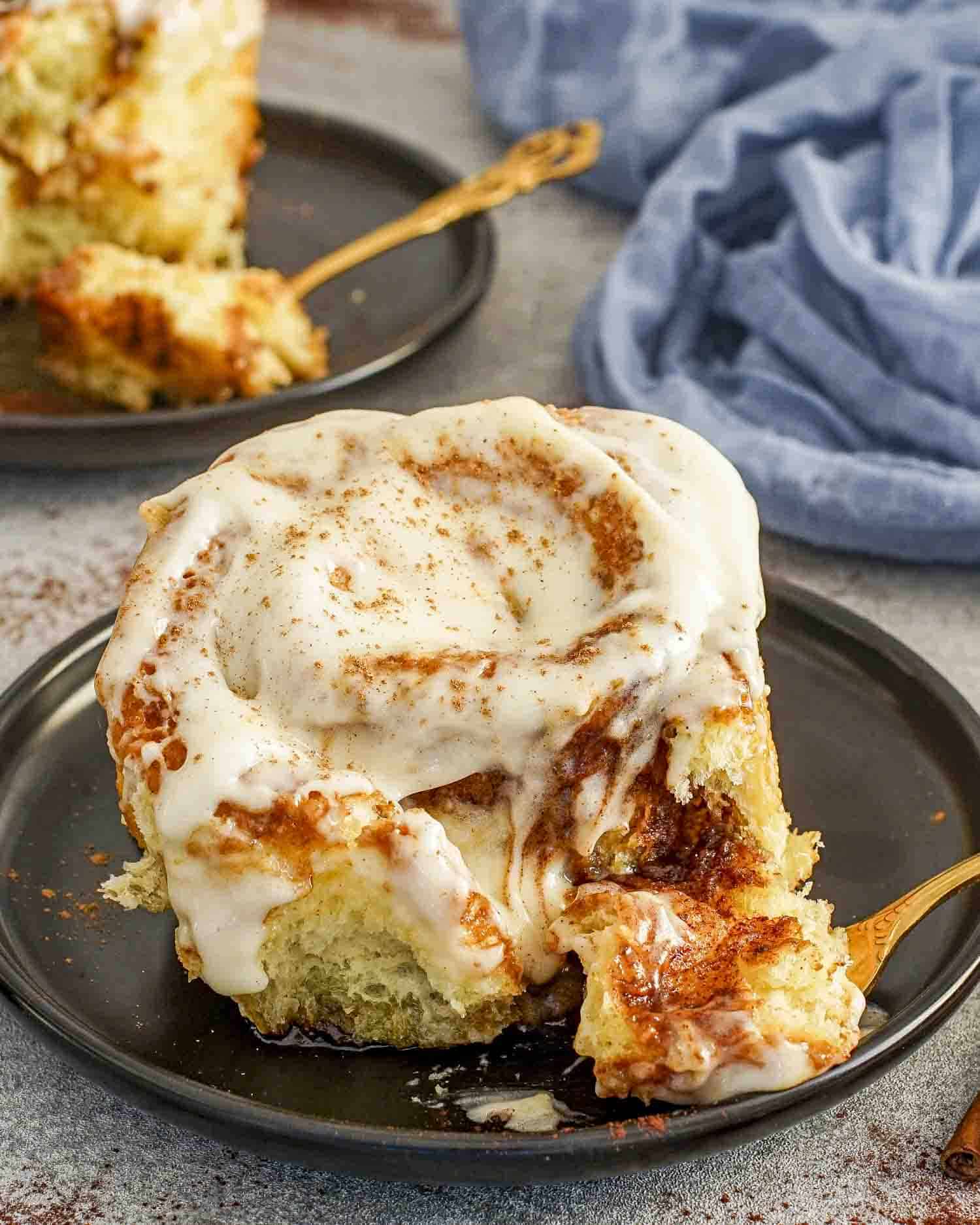 a delicious gooey cinnamon roll with icing on a plate.