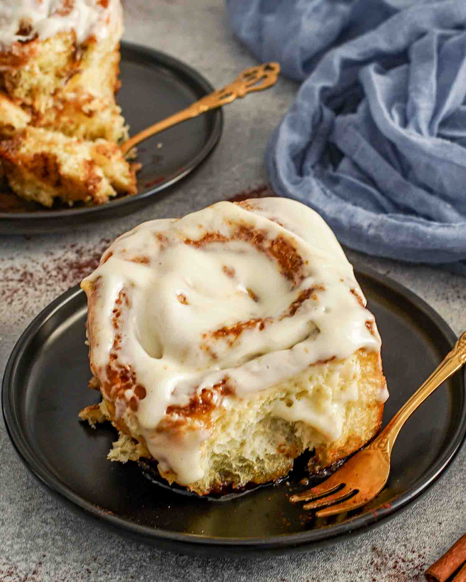 a delicious gooey cinnamon roll with icing on a plate.