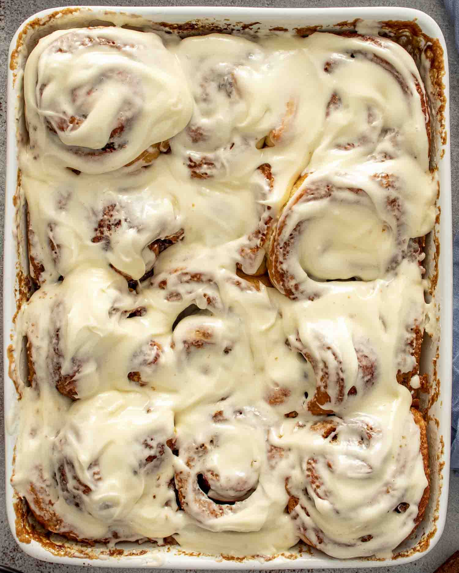 a pan of freshly made cinnamon rolls with icing.
