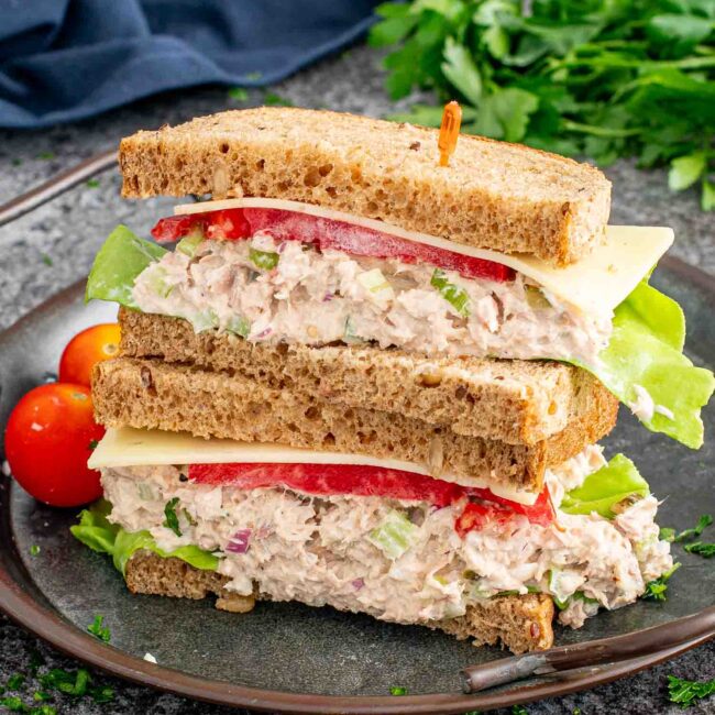 a tuna salad sandwich cut in half on a plate.