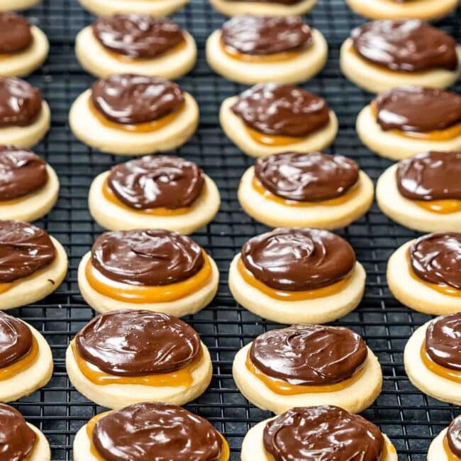 freshly made twix cookies on a black cooling rack.