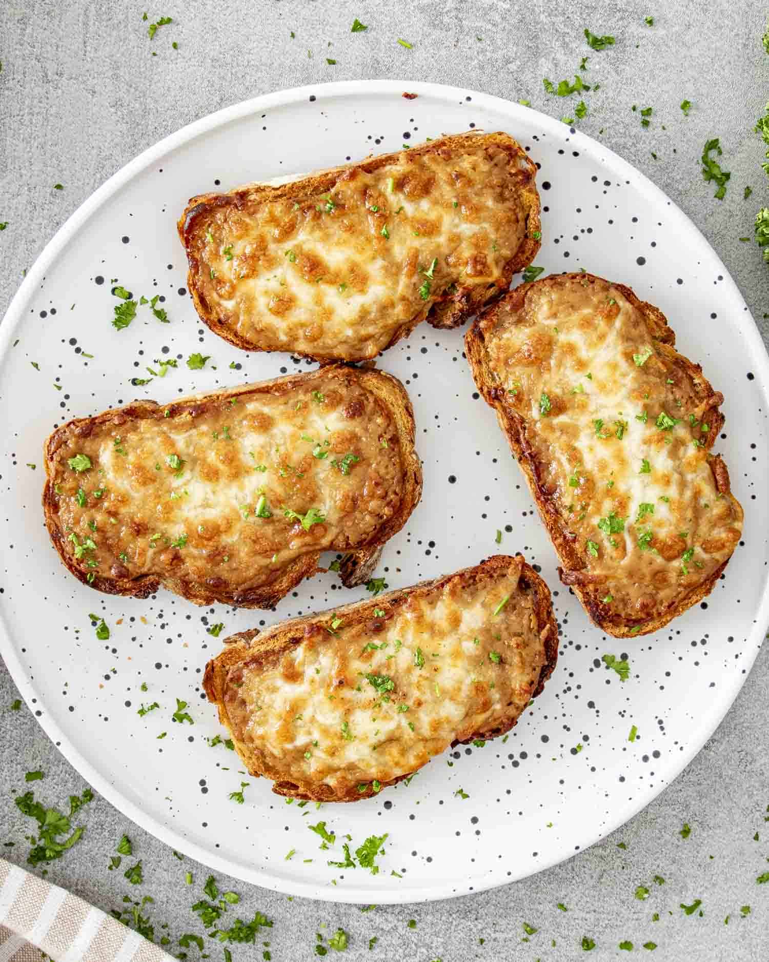 4 slices of walsh rarebit on a plate garnished with some parsley.