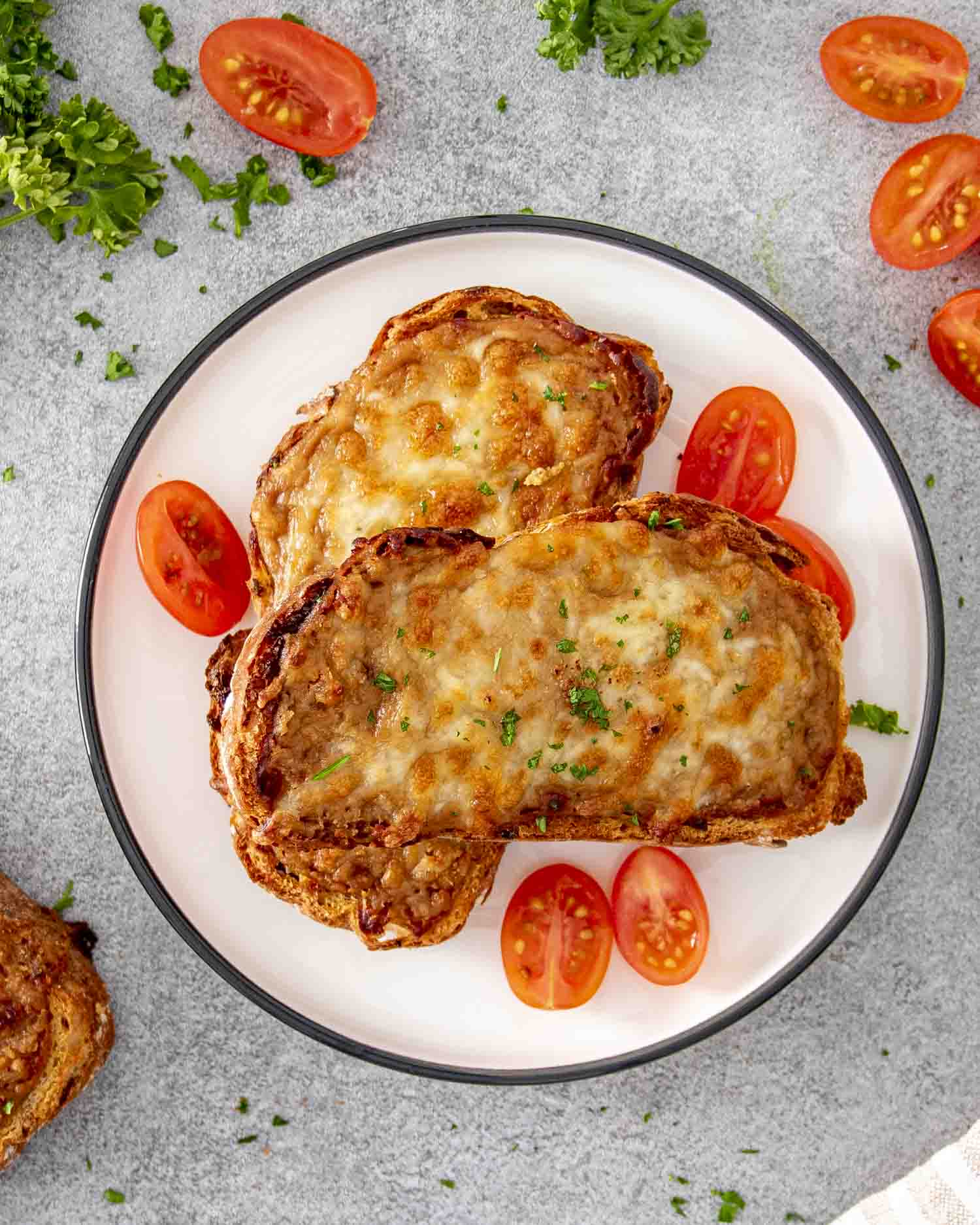 a couple slices of walsh rarebit on a white plate garnished with some parsley.