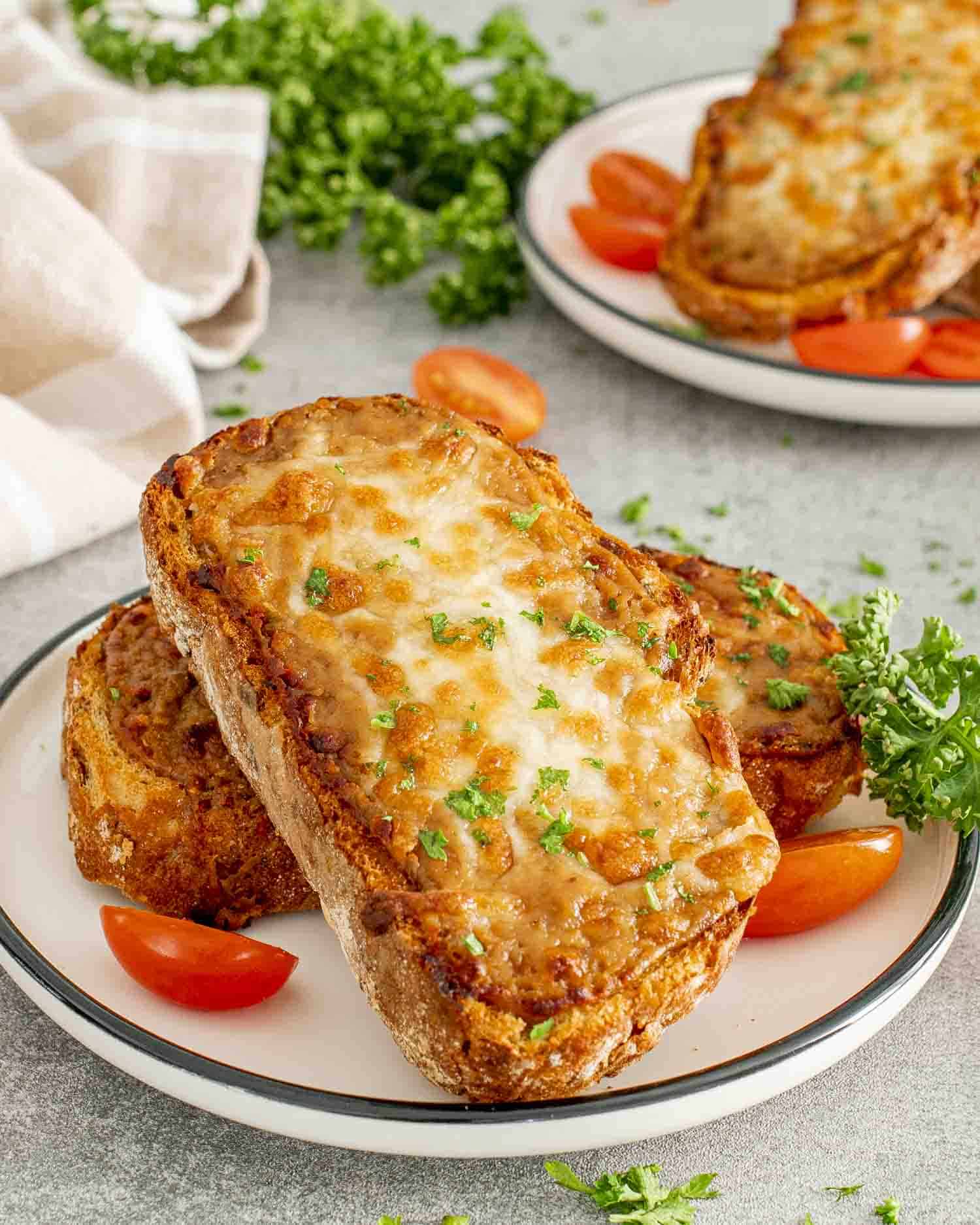 a couple slices of walsh rarebit on a white plate garnished with some parsley.
