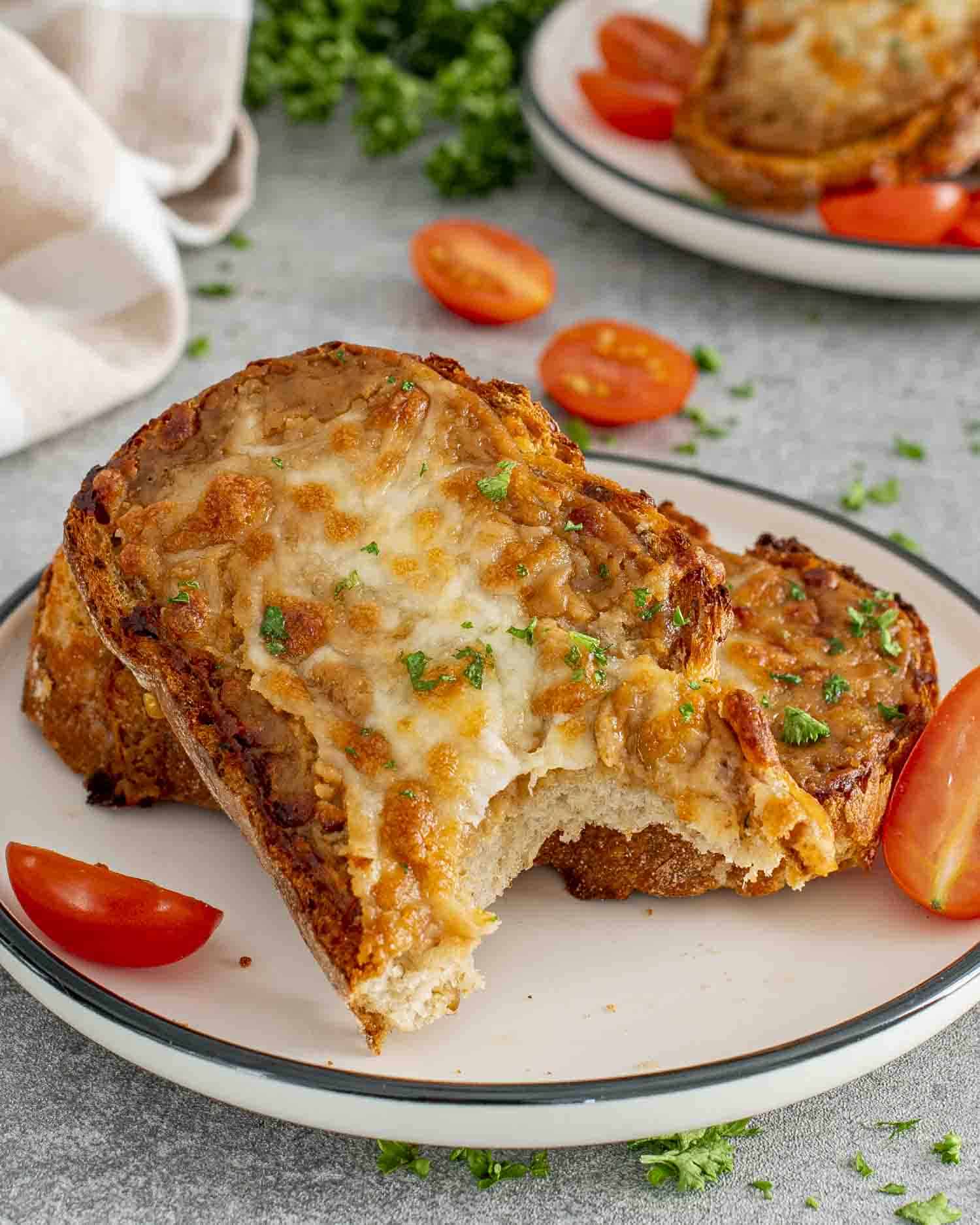 a couple slices of walsh rarebit on a white plate garnished with some parsley.